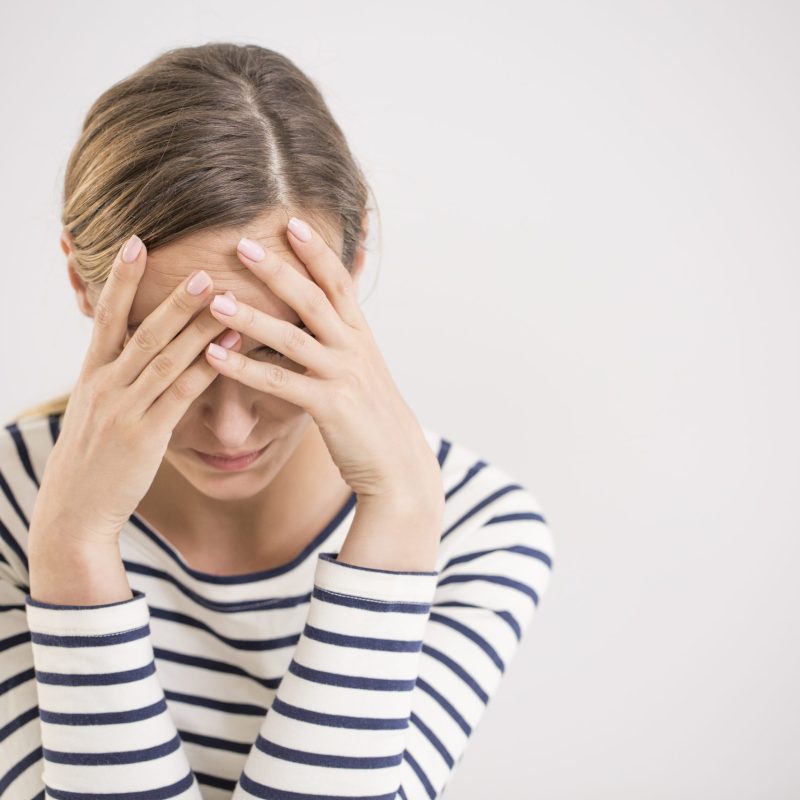 Young hopeless woman suffering from depression having nervous breakdown holding her head on isolated background, copy space